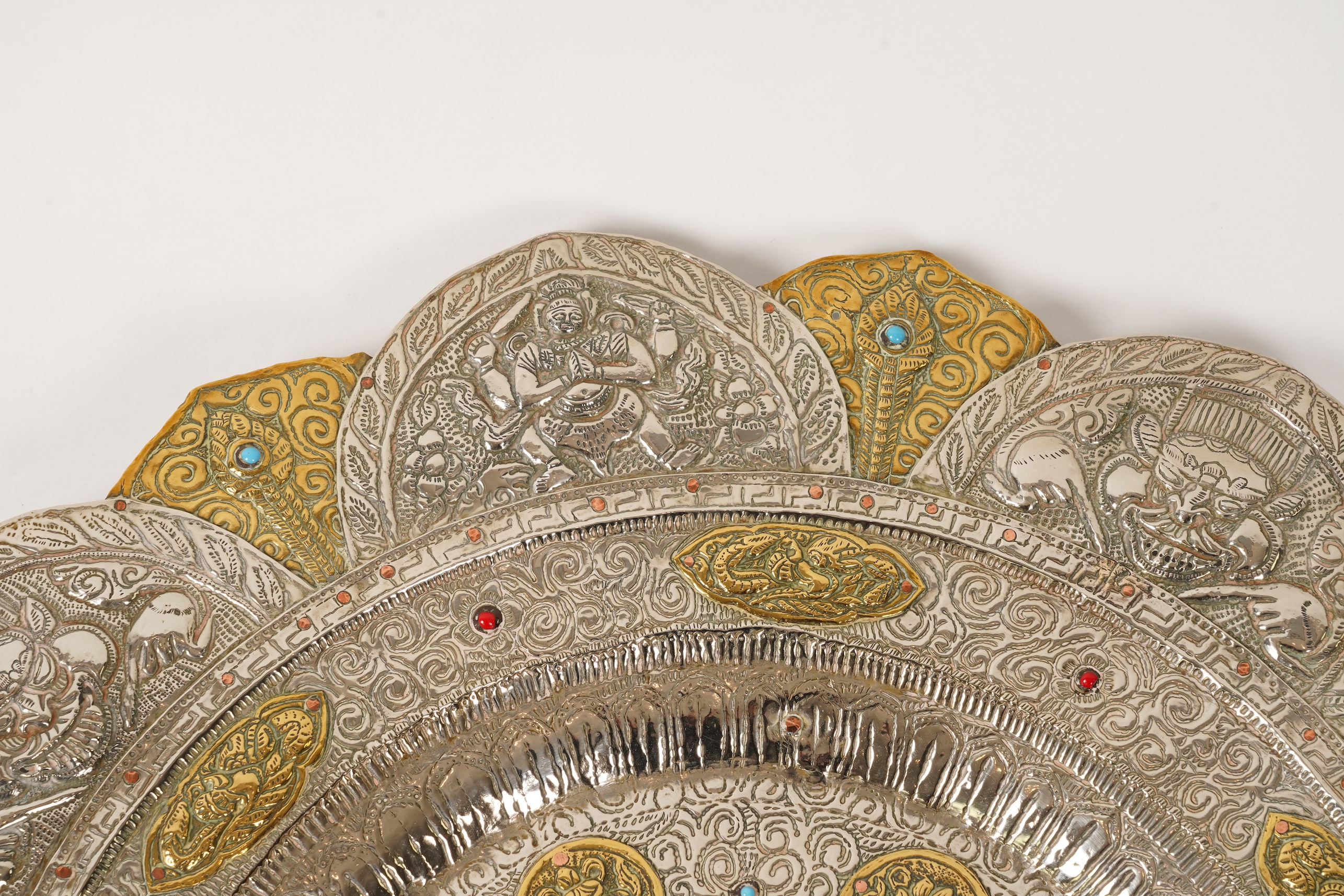 A graduated set of three Nepalese repoussé white metal and brass chargers, first half 20th century